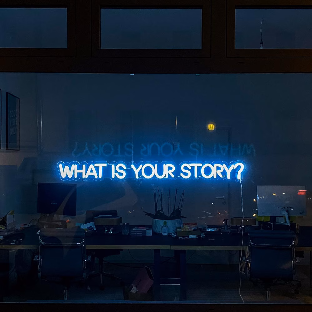 Inspirierendes Bürodesign mit Leuchtreklame ‘What’s your Story’ als Teil der Firmengeschichte und Story-Seite der RACHNY System GmbH.